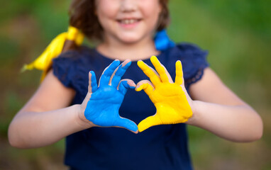 Love Ukraine concept. Little girl show hands in heart form painted in Ukraine flag color - yellow...