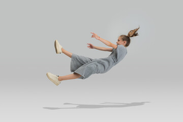 Studio shot of little preschool caucasian girl in casual clothes falling down isolated over white studio background. - obrazy, fototapety, plakaty