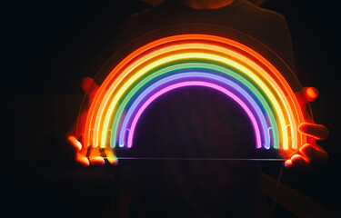 Guy holds neon led rainbow in hands in the night