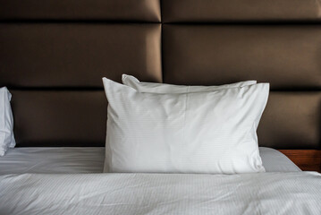 Close up white soft pillows on bed in cosy and luxury hotel room. Bed maid luxury ideas concept.