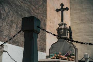 Detail of a stone object with chains surrounding a grave in a cemetery