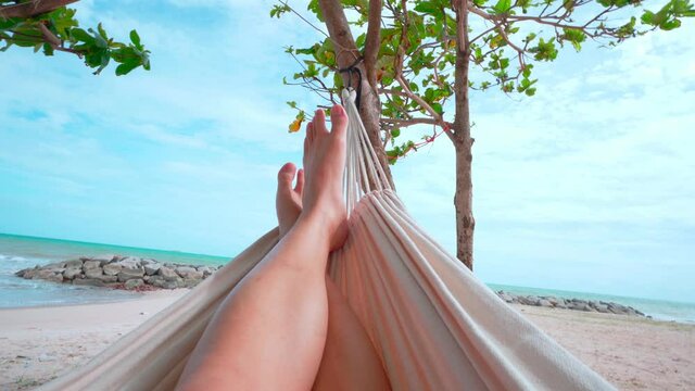 Hello Summer man relaxing in hammock tanning on the beach happy sunbathing during summer holidays. on tropical vacations.
