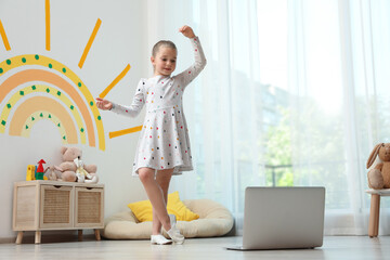 Cute little girl taking online dance class at home