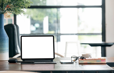 Mockup blank screen tablet with keyboard and supplies on wooden table in dark tone office room.