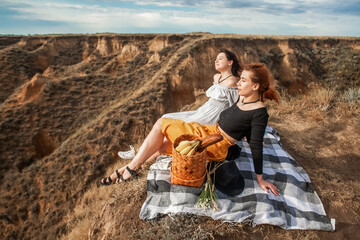 two women enjoy a beautiful view on the edge of a cliff in a deserted place in summer