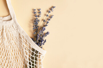 Natural mesh bag with a bouquet of lavender on a light background. Zero waste. Flat lay, place for text.