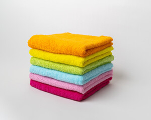 Obraz na płótnie Canvas Colored cotton terry towels for face, hands and feet close-up on a white background. Orange, yellow, light green, blue, pink and burgundy towel. Concept: textile accessories for shower, spa, hotels