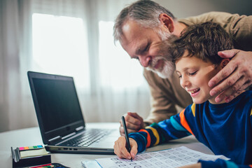 Child practicing writing at home with the help of his father