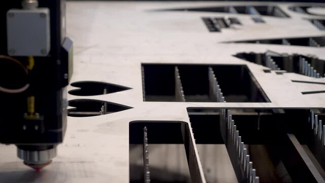 Robotic machine with laser for metal cutting. HDR. Close-up of industrial laser cuts patterns on metal sheet. Modern laser machine at industrial factory
