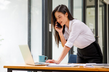 Obraz premium Portrait of beautiful Young asian businesswoman sitting at desk and using laptop in work office,Successful confident japanese female office worker,