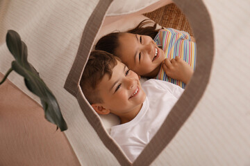 Cute little children lying in toy wigwam at home © New Africa