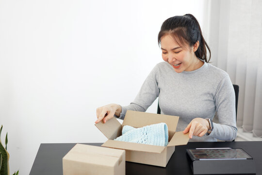 Shopping online concept a smiling woman unboxing an arriving parcel to check the products she bought after waiting with an effort