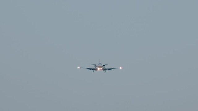 Private luxury jet is approaching the airport. View of airplane in the sky. Aircraft descend towards the camera. Slow motion