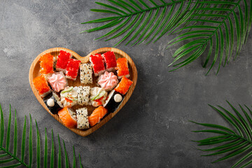 Japanese rolls in heart shaped plate on gray concrete background top view copy space for text