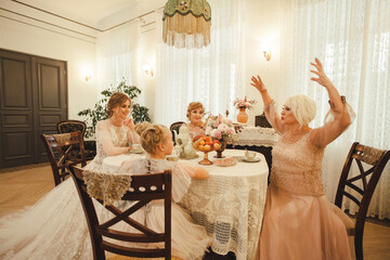 Senior, mid age, young adult woman and child.  Females women of different ages sit at vintage table...