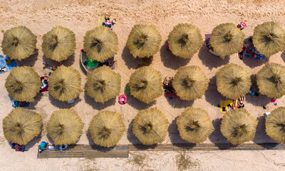 Aerial. Thatched umbrellas on the beach by the sea. Top view from drone.