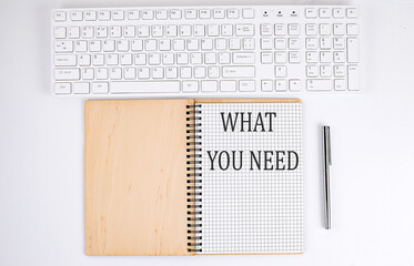 WHAT YOU NEED text on the notebook with keyboard on white background