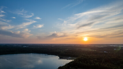 Obraz premium Aerial view shot by a drone of a beautiful dramatic and colorful sunset at coast of the lake. Nature landscape. Nature in Europe. reflection, blue sky and yellow sunlight. landscape during sunrise or