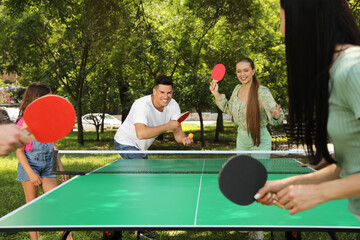 Happy family with child playing ping pong in park