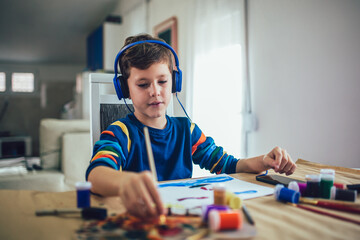 Cute little boy painting a picture in home studio