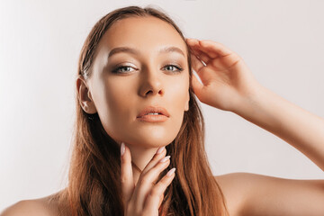 Fototapeta premium Beautiful young girl smiling and posing looking at the camera on a white isolated background with mockup. Positive brunette woman. Kind look. Beauty face