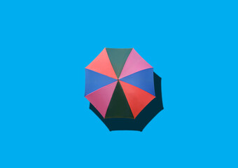 Obraz premium Top view, Single rainbow umbrella isolated on cyan background for stock photo or design, invesment, business, summer concept