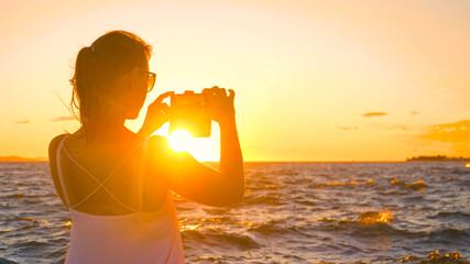 CLOSE UP: Young woman on vacation in Zadar is taking photos of the sunset.