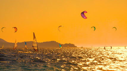 Energetic tourists are windsurfing in coastal Croatia on a sunny summer evening.