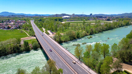 AERIAL: Flying above a highway bridge crossing an emerald river in Slovenia
