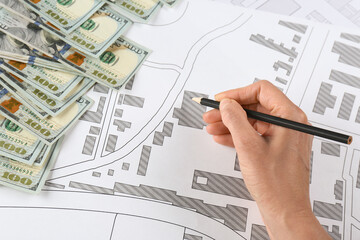 Cartographer with money drawing cadastral map, closeup