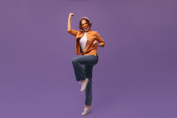 Full-length portrait of moving young girl at studio. Young short-haired lady wearing orange shirt...