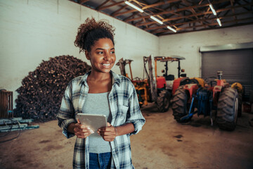 Mixed race female standing in farm store room organising layout using digital tablet 