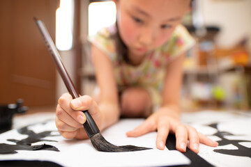 自宅で習字をする少女