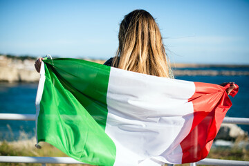 A tourist woman with italian flag looking the sea side