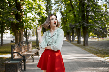 pretty blonde in red skirt outdoors in the park green trees