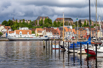 Fototapeta na wymiar Sail boats in the port of Flensburg, St. Jorgen's Church in the background. Schleswig-Holstein in Germany