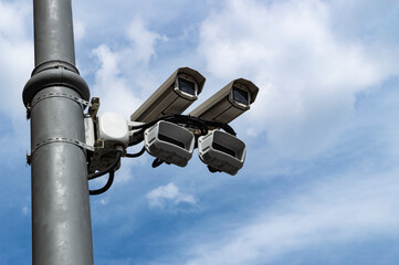 The pair of surveillance cameras on a metal pole against the blue sky