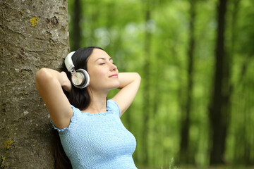 Asian woman resting listening to music in a forest