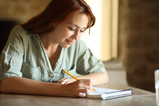 Woman drawing or taking notes on notebook at home