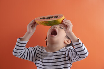 little boy holding papaya fruit while