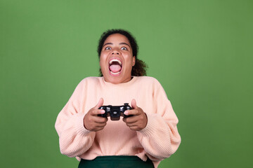 Beautiful african american woman on green background focused playing video games