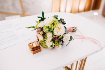Wedding rings on the table near the wedding bouquet