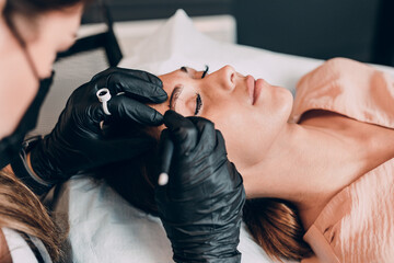 Eyebrows microblading concept.  Beautician is wearing face protective masks due to Covid-19...