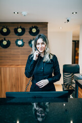 Beautiful young woman working at hotel reception or check out