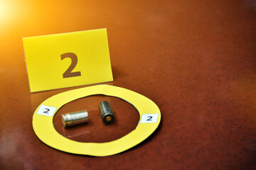 Pistol's bullet shells and yellow number paper sign on floor, concept for keeping evidence of the...