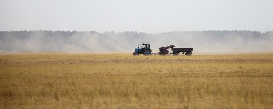 Harvested linen field panorama with tractor harvester trailer,  linum harvesting at summmer day, European farm landscape