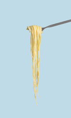 Cooked spaghetti in fork on pastel background