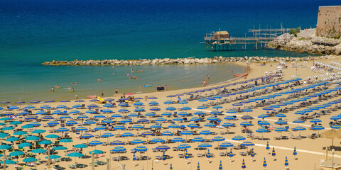 Summertime relaxing panorama of an italian sand beach with beautiful blue sea and colorful umbrellas