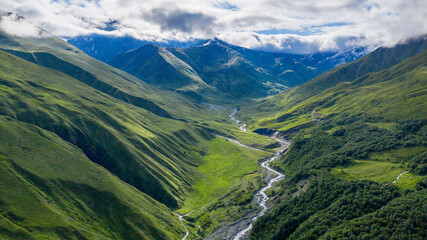 Panoramic aerial view of Balkarsky Cherek river valley and Great Caucasus Range on sunny summer day. Kabardino-Balkaria, Russia.