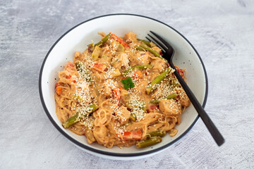 vegan thai stiry fry with peanut lime sauce and vermicelli noodles topped with sesame seeds, healthy plant-based food